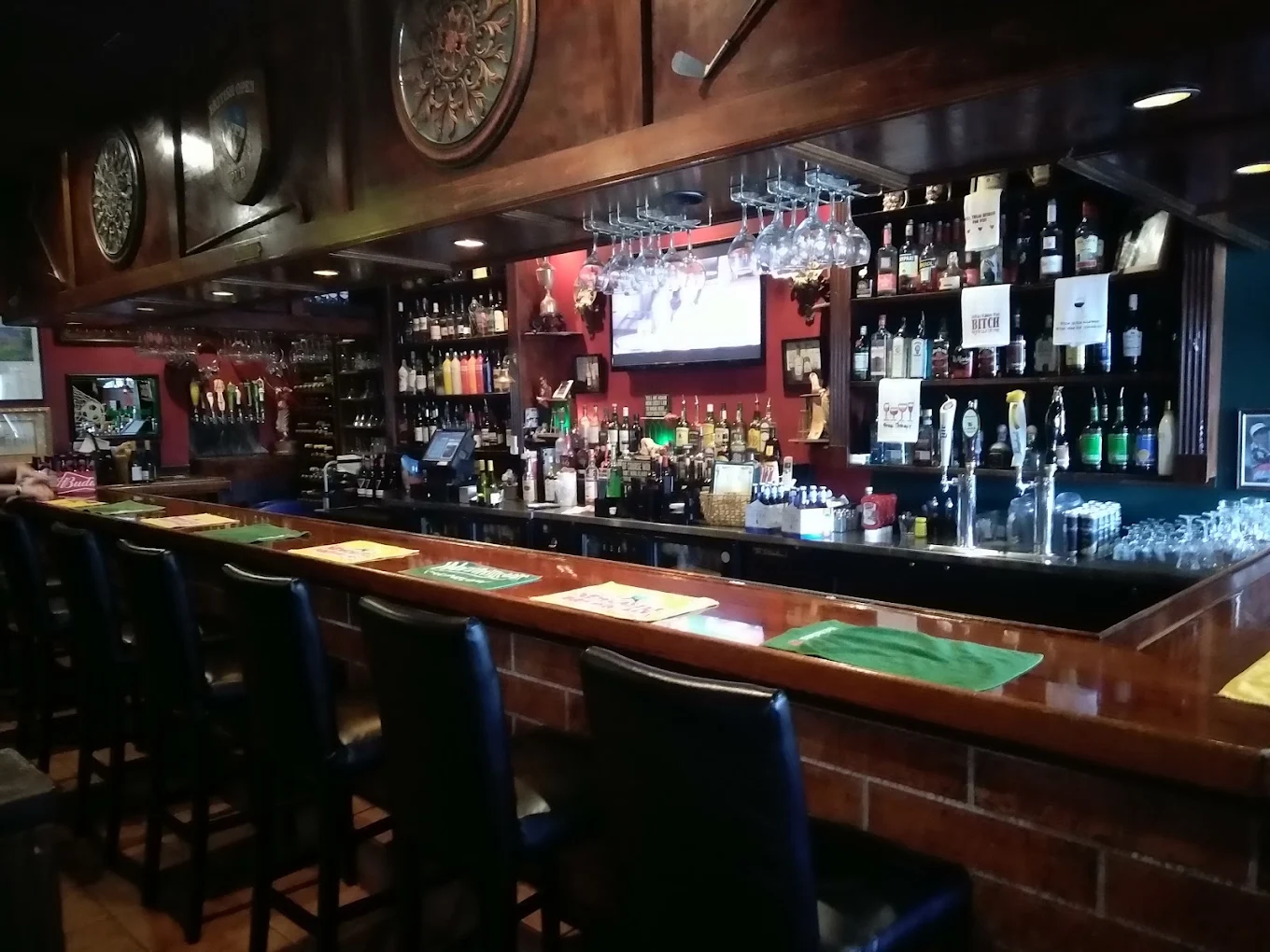 Bar counter with stools, hanging wine glasses, and bottles on shelves