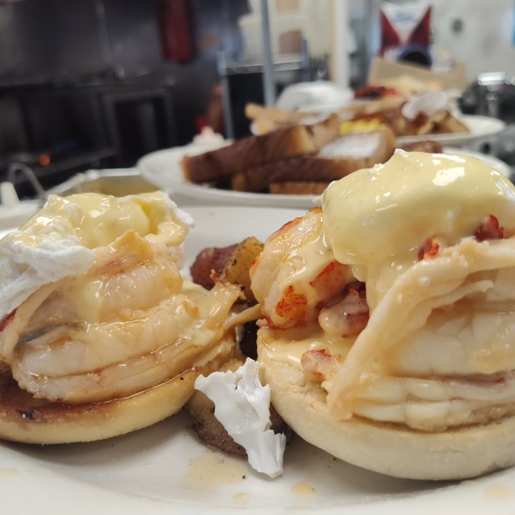 Close-up of eggs Benedict topped with lobster and hollandaise
