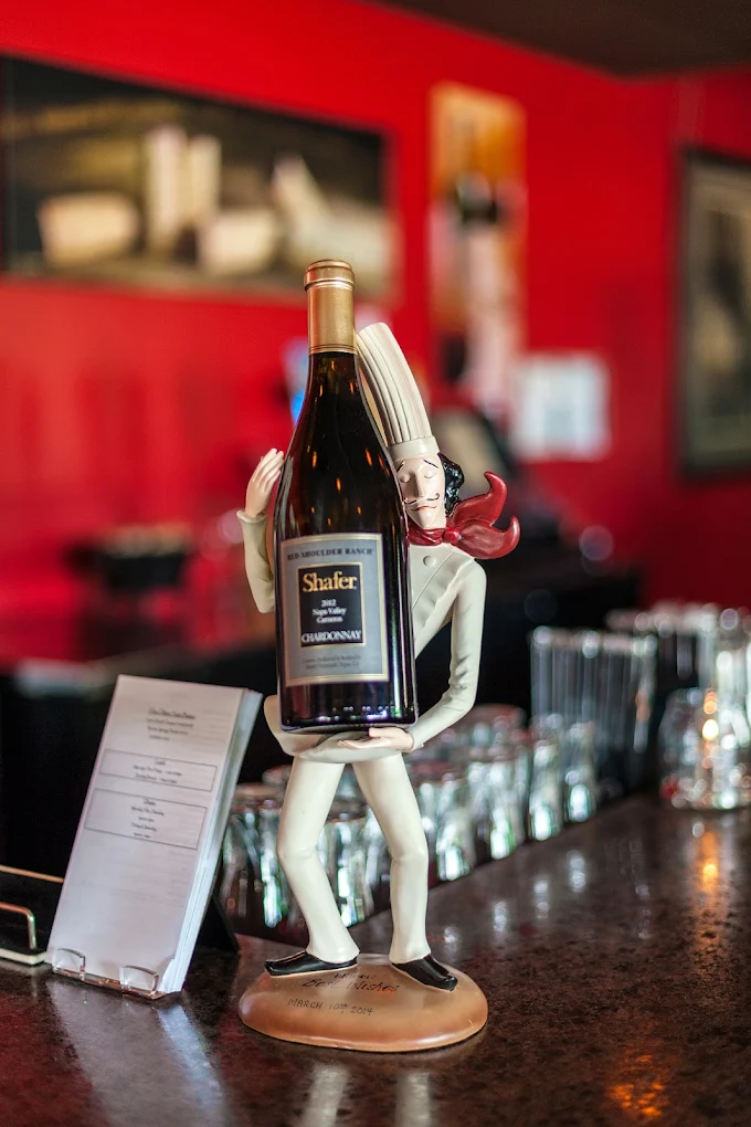Chef figurine holding a wine bottle on a bar counter