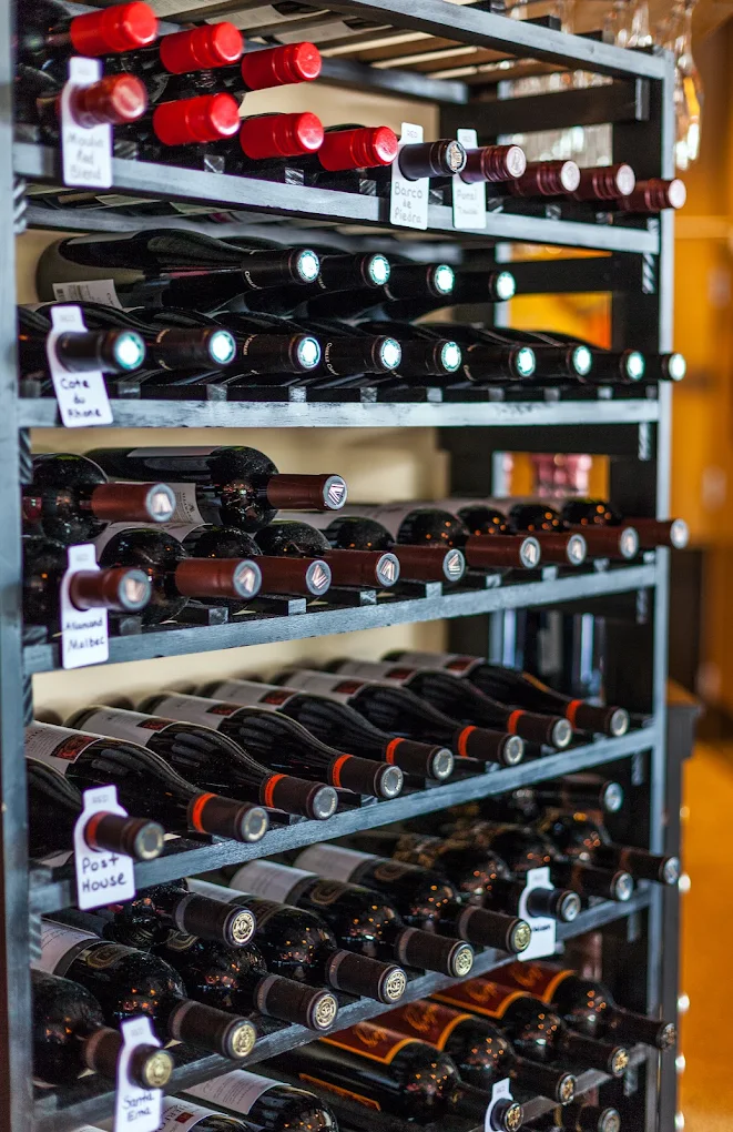 Close-up of labeled wine bottles stored horizontally on metal racks