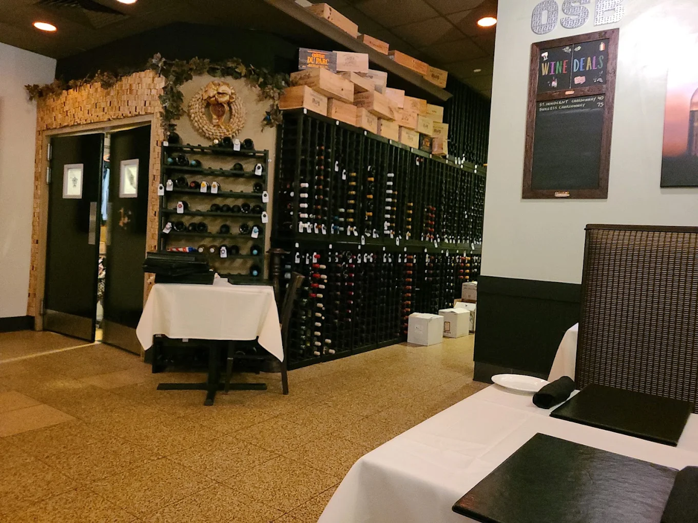 Wine racks beside tables set with white tablecloths and dark napkins